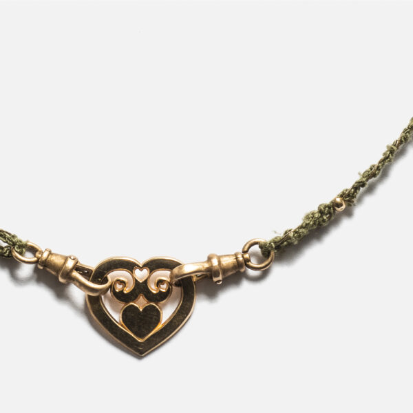 Collier monté sur un cordon Mokuba de couleur kaki avec en son centre un coeur en plaqué Or 18 carats entouré de fermoirs recyclés en bronze